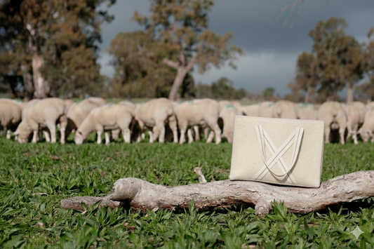 Everyday wool bag in natural wool with cotton handles and cotton lining, showcasing versatile design for daily use and travel. Bag is in a beautiful paddock with sheep in the background representing the wool use in the bag.