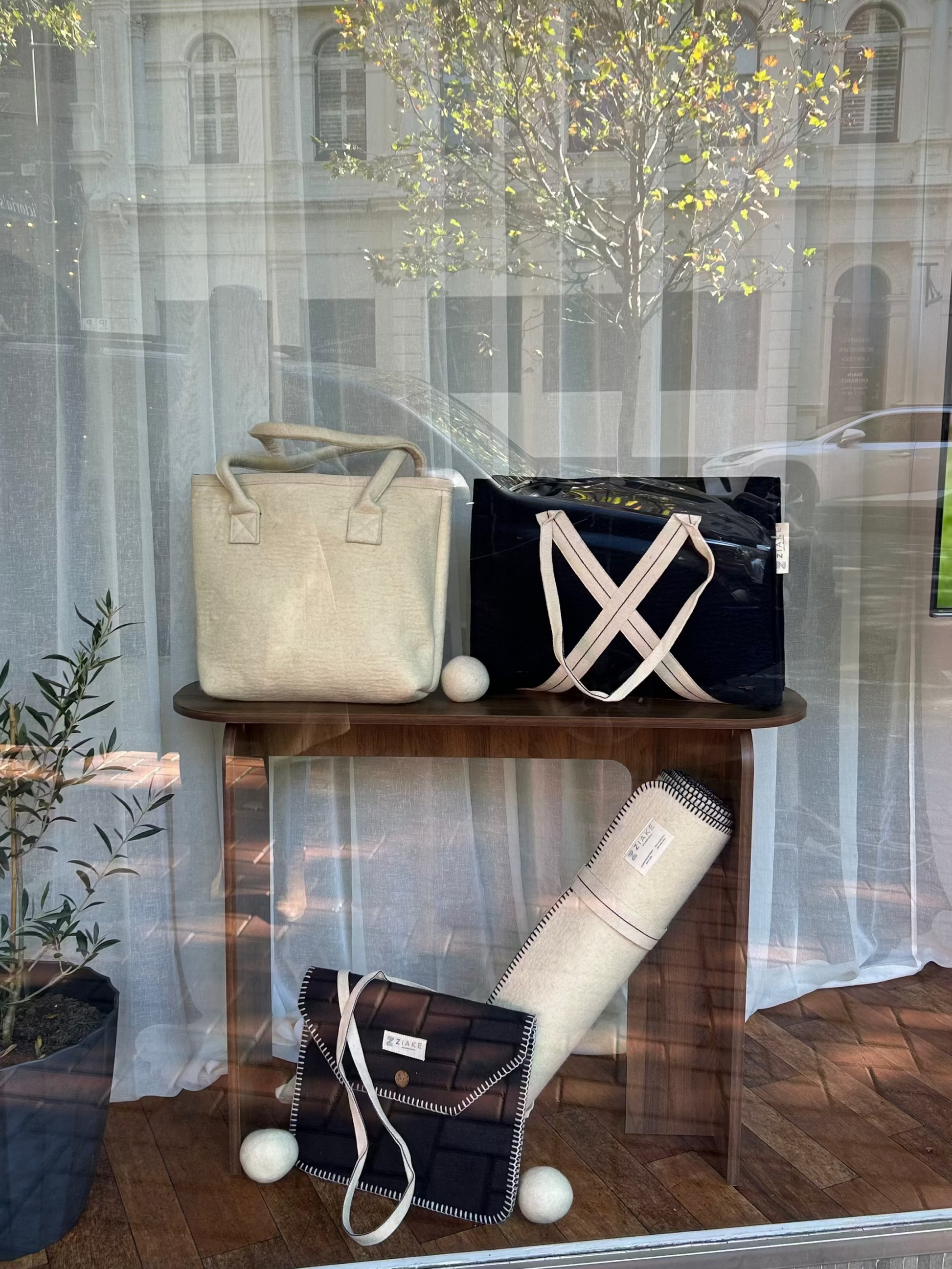 A display of Australian crossbred wool bags and a yoga mat in front of a building with a glass window.