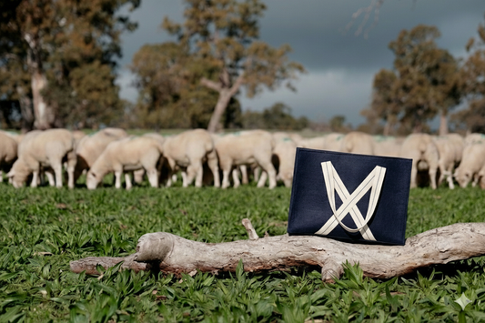 Everyday wool bag in navy with cotton handles and cotton lining, showcasing versatile design for daily use and travel.  Bag is in a beautiful paddock with sheep in the background representing the wool use in the bag. 